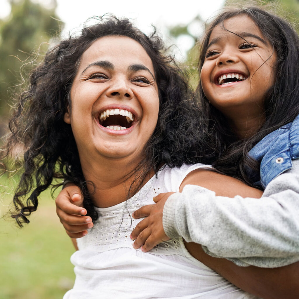 Mom with daughter on her back laughing.